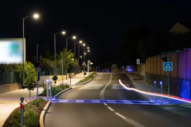 Avenue éclairée de nuit par des candélabres LED, avec bornes lumineuses et passage piéton, à La Garde (Var)