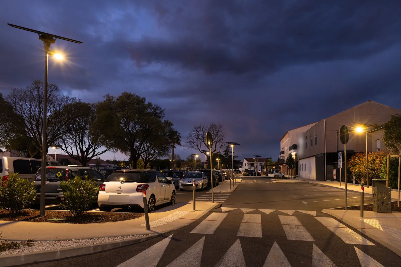 Parking De Lattre de Tassigny éclairé à la tombée de la nuit par des mâts solaires, à La Crau (Var)